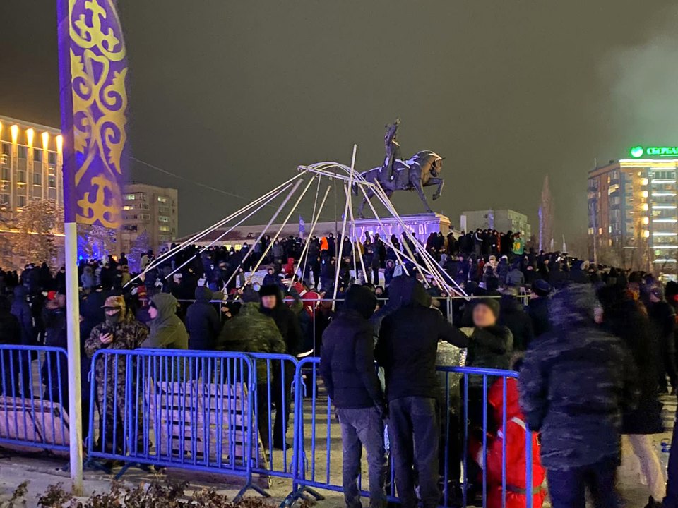Люди у ограждения на площади; на заднем плане виден конный памятник.